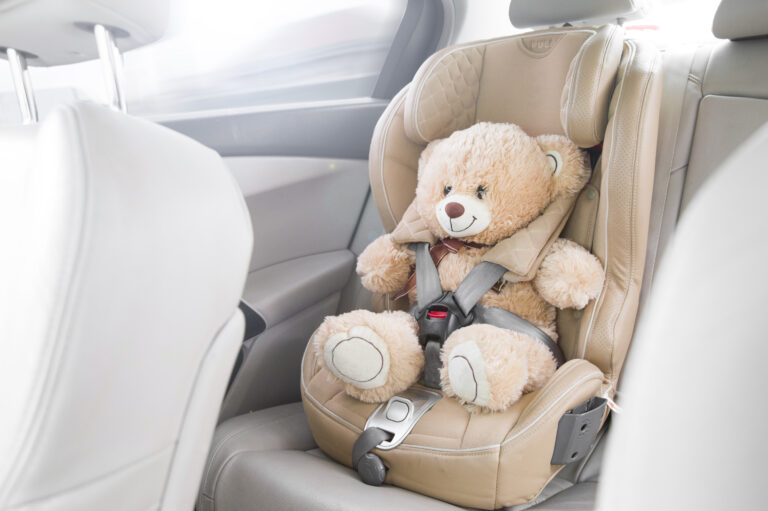 Safety car seat for baby with beige teddy bear.